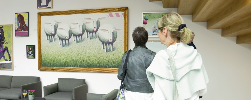 Zwei Personen an der Treppe des ILB-Foyers schauen Kunstausstellung an