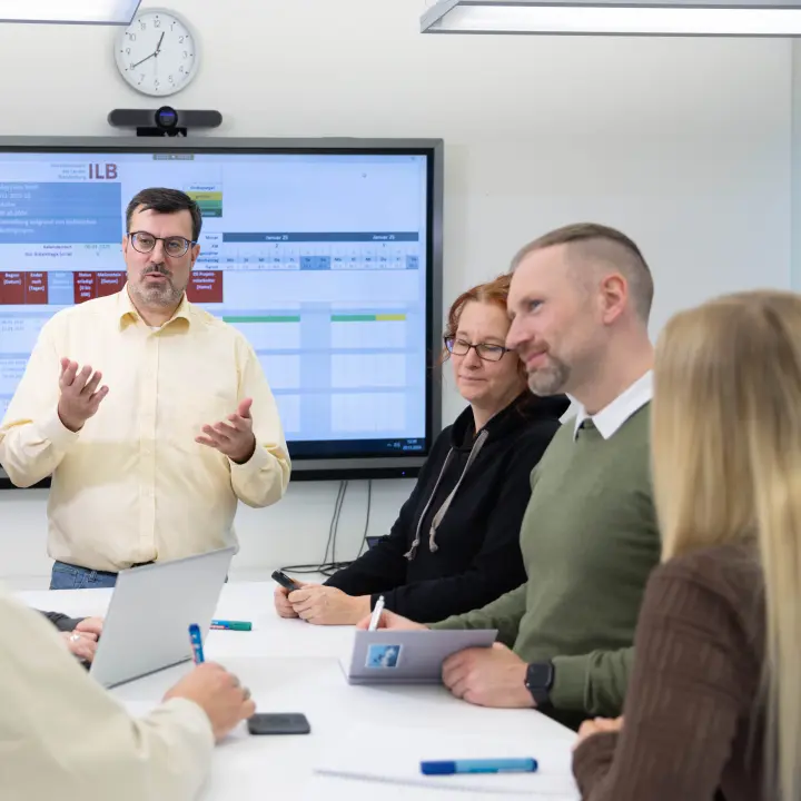 Unscharfes Bild mit einem Menschen vor einem projizierten Bühnenbild und Publikum